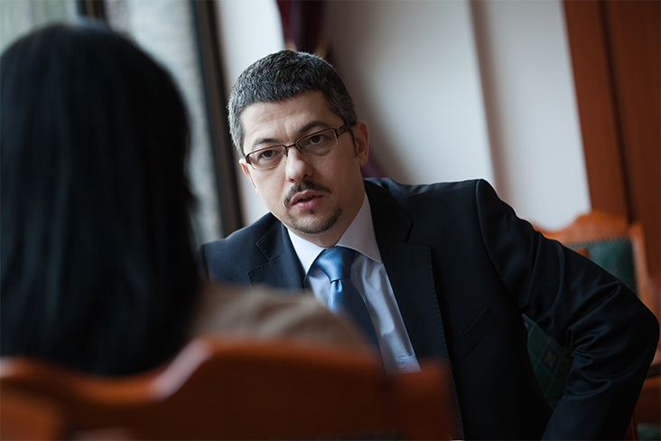 A man in suit and tie sitting at a table.